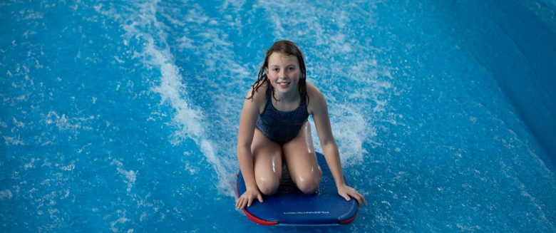 Kind surft auf dem Flowrider