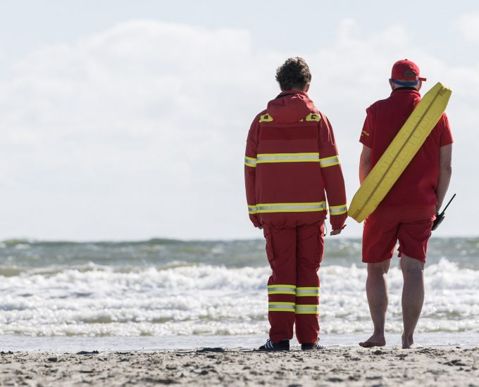 Die DLRG steht am Ufer und schaut auf das Meer hinaus